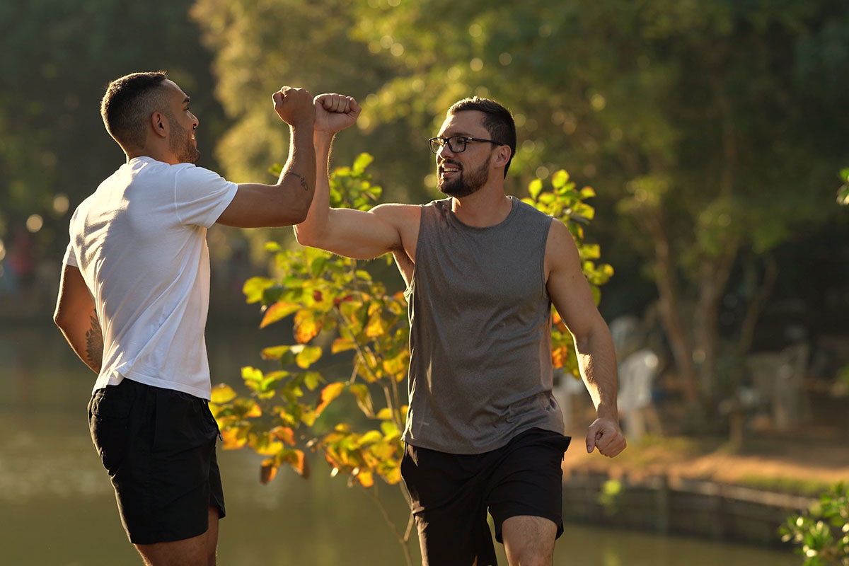 Fitness men greeting each other outdoors