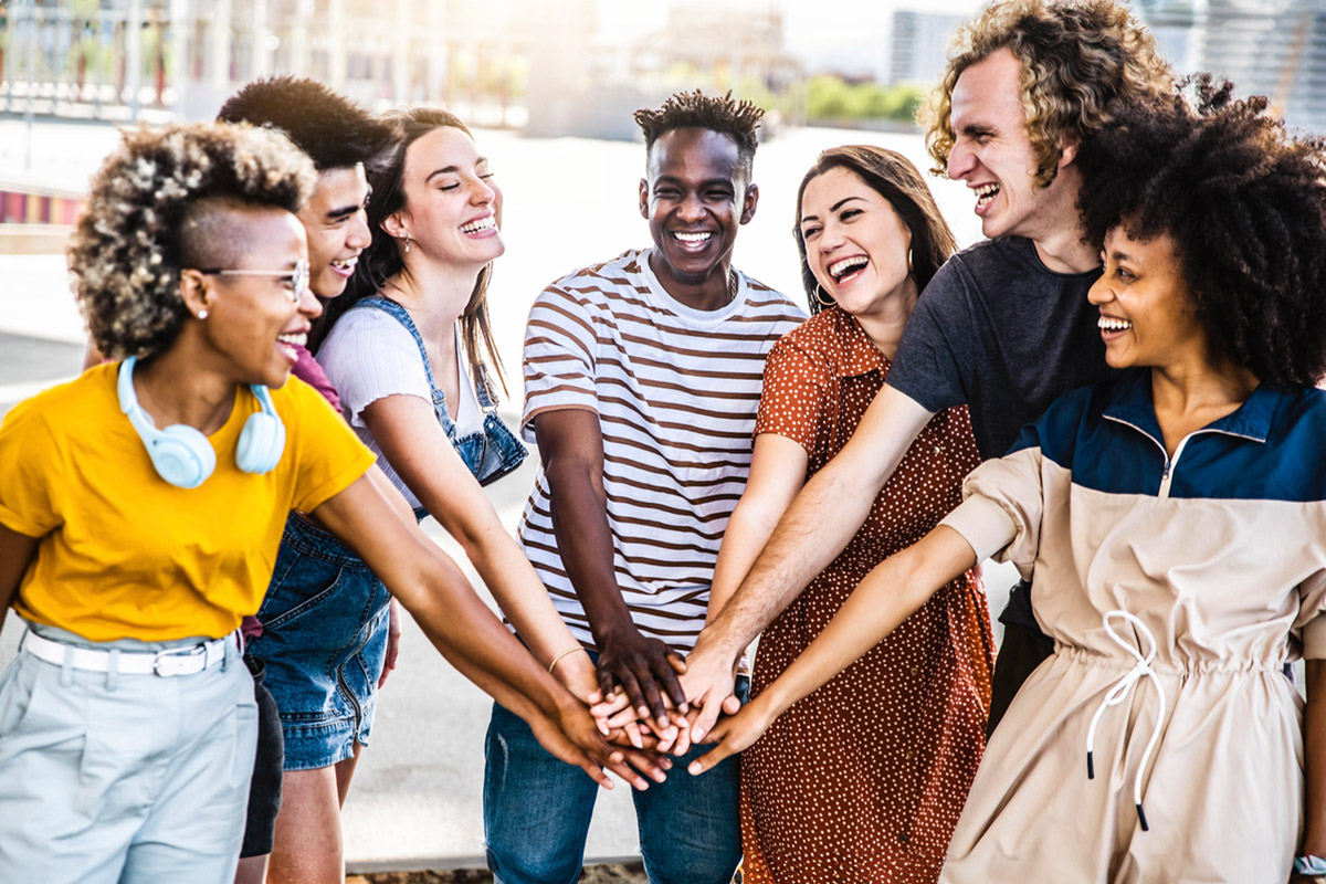 Multiracial happy young people putting their hands on top of each other - Diverse friends unity togetherness in volunteer community - Concept about college, relationship, creative, youth and community.