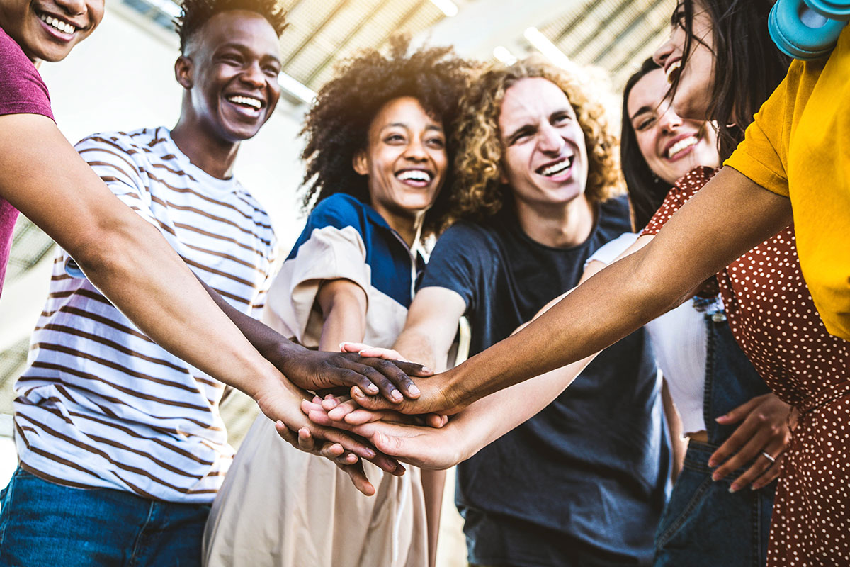 Multiracial happy young people stacking hands outside - Diverse friends unity togetherness in volunteer community - Concept about university, relationship, creative, youth and human resources